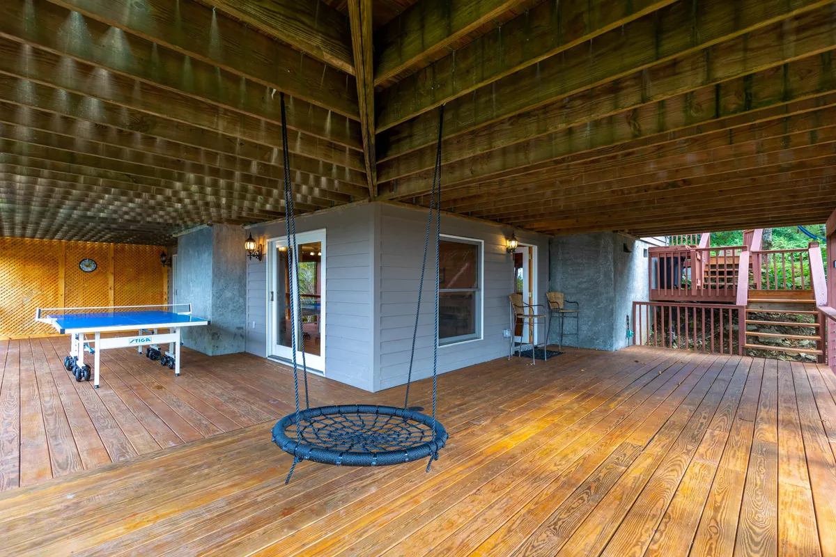 A lively outdoor area featuring a swing seat, a ping pong table, and a view of the house’s exterior. The space is casual and fun, designed for social gatherings, active play, or relaxing between excursions.