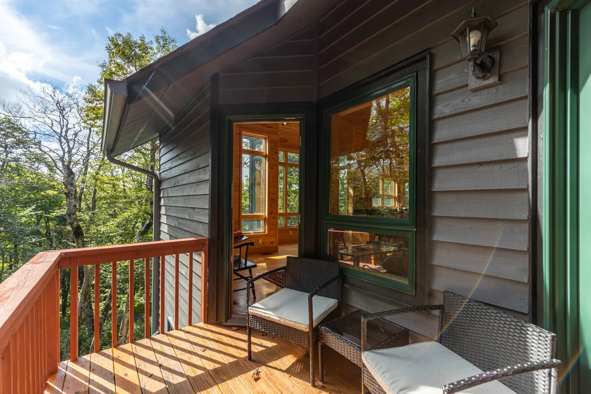 A spacious deck featuring comfortable chairs and broad views of nature beyond. The deck looks ideal for relaxing, reading, or simply soaking in the tranquil ambiance of the mountains.